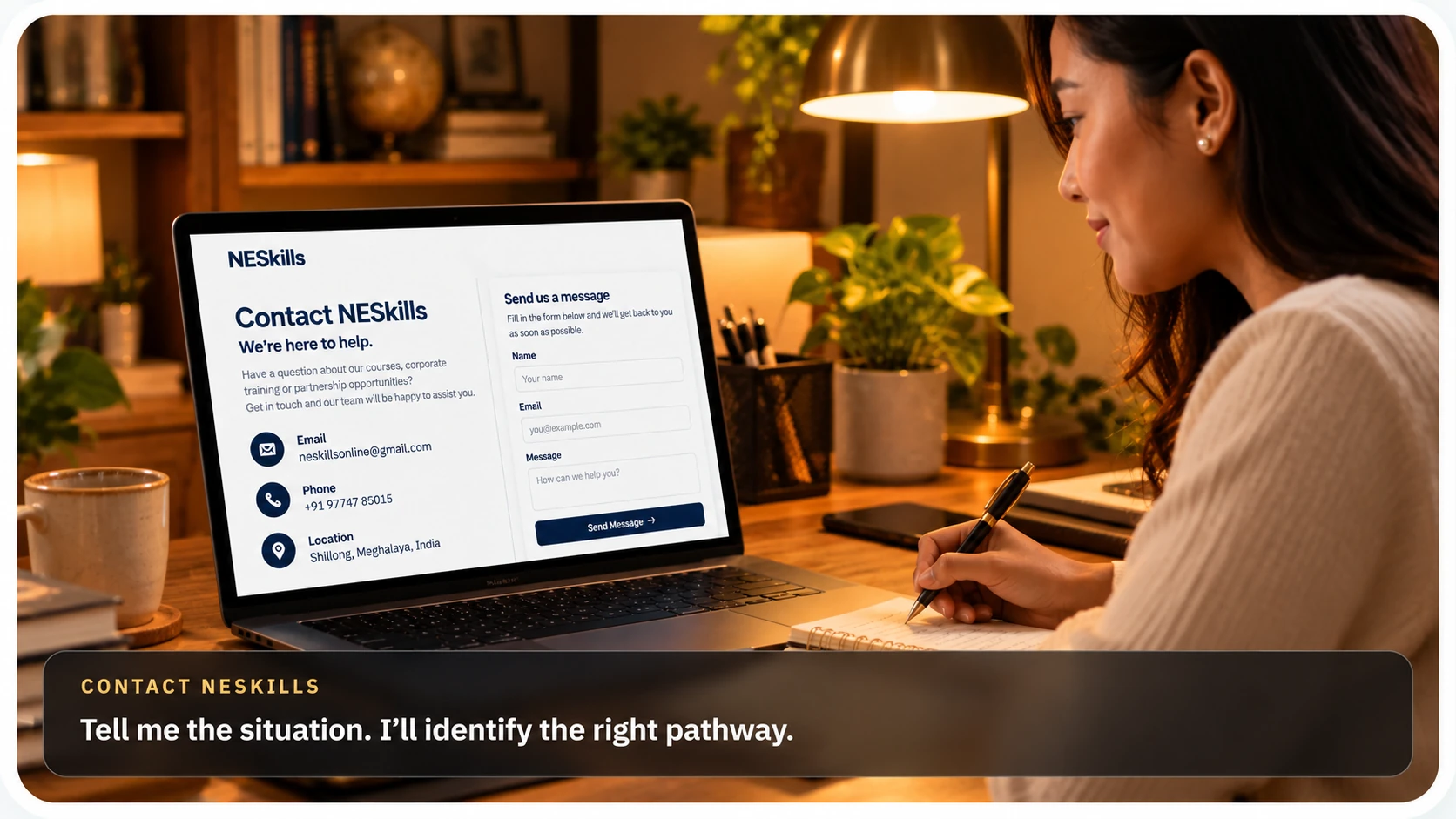A woman writing at her desk beside a laptop showing the NESkills contact page