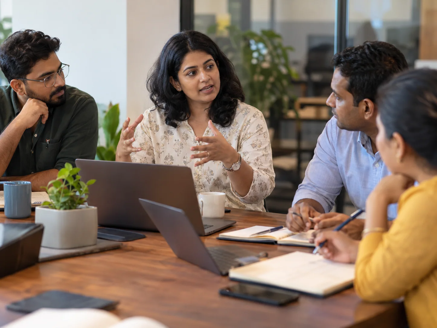 Three Indian millennial coworkers have an engaged team discussion around a desk in an Indian office