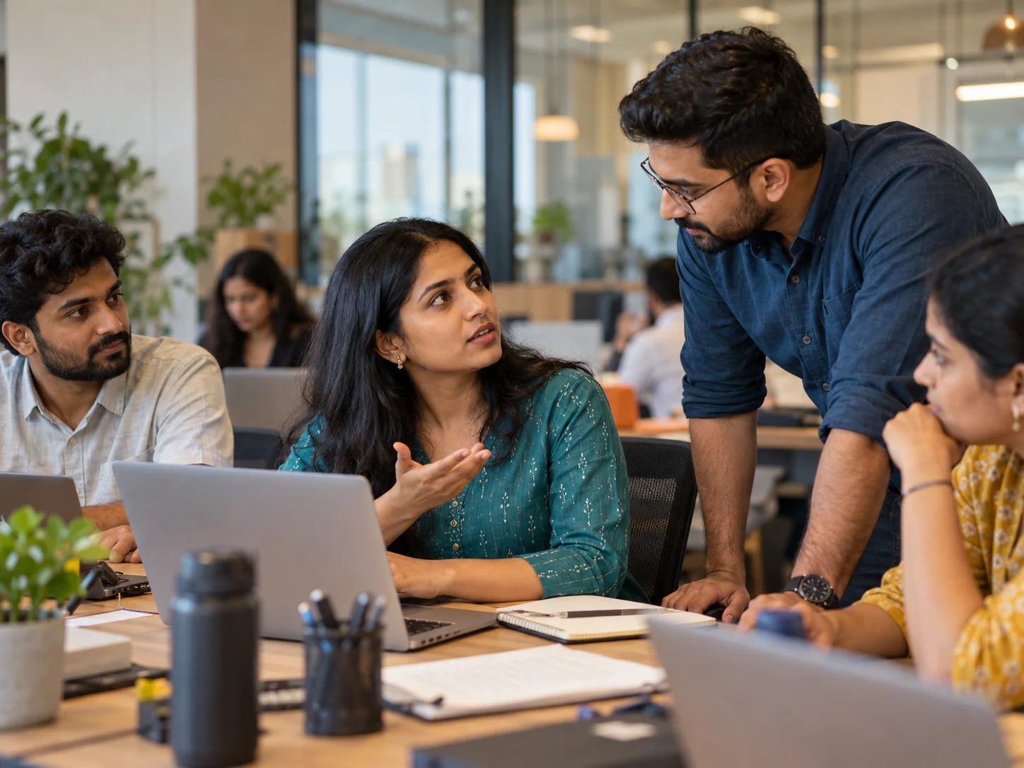 An Indian millennial woman raises a question to clarify instructions from her coworker at an office table